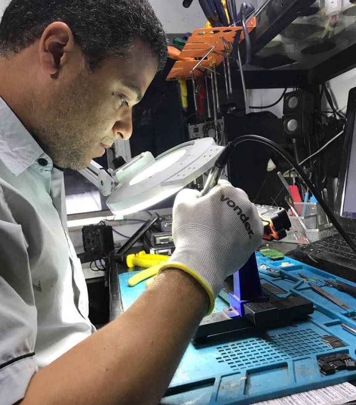 Pessoa reparando Circuito eletrônico com lupa